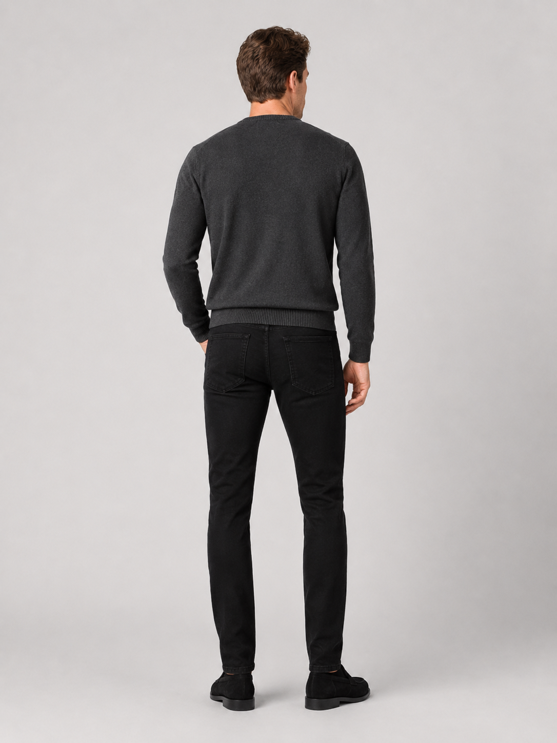 Back view of a man wearing black slim fit stretch denim jeans showing the tailored silhouette, rear pockets, and comfortable everyday fit