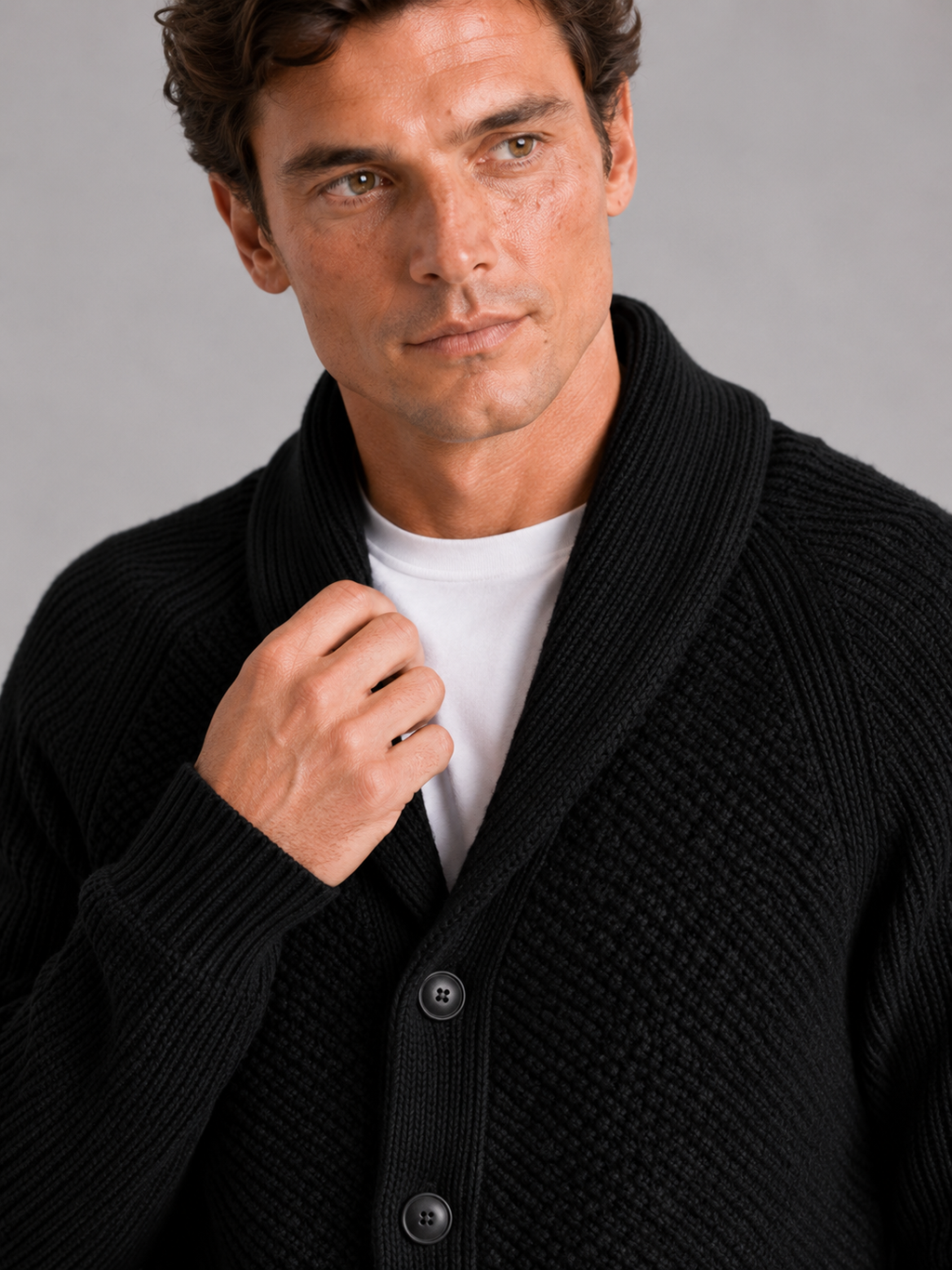 Close up of black knit cardigan showing soft textured fabric and front pocket detail