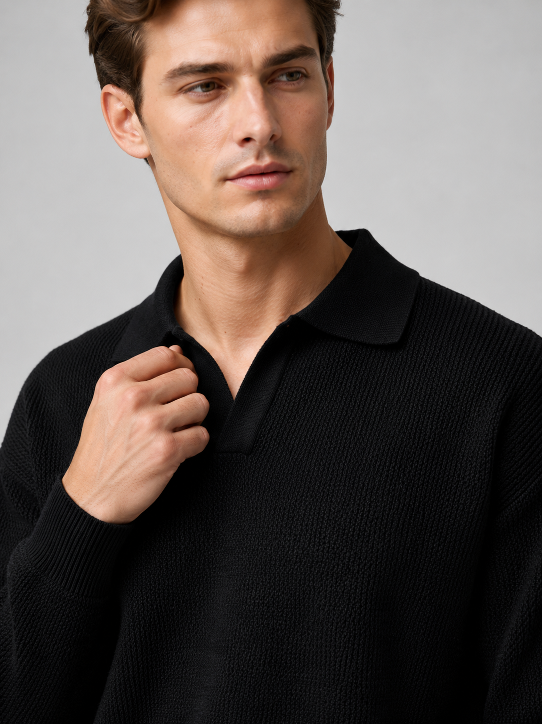 Close up of black knit polo sweater showing soft textured fabric and refined v neck collar detail