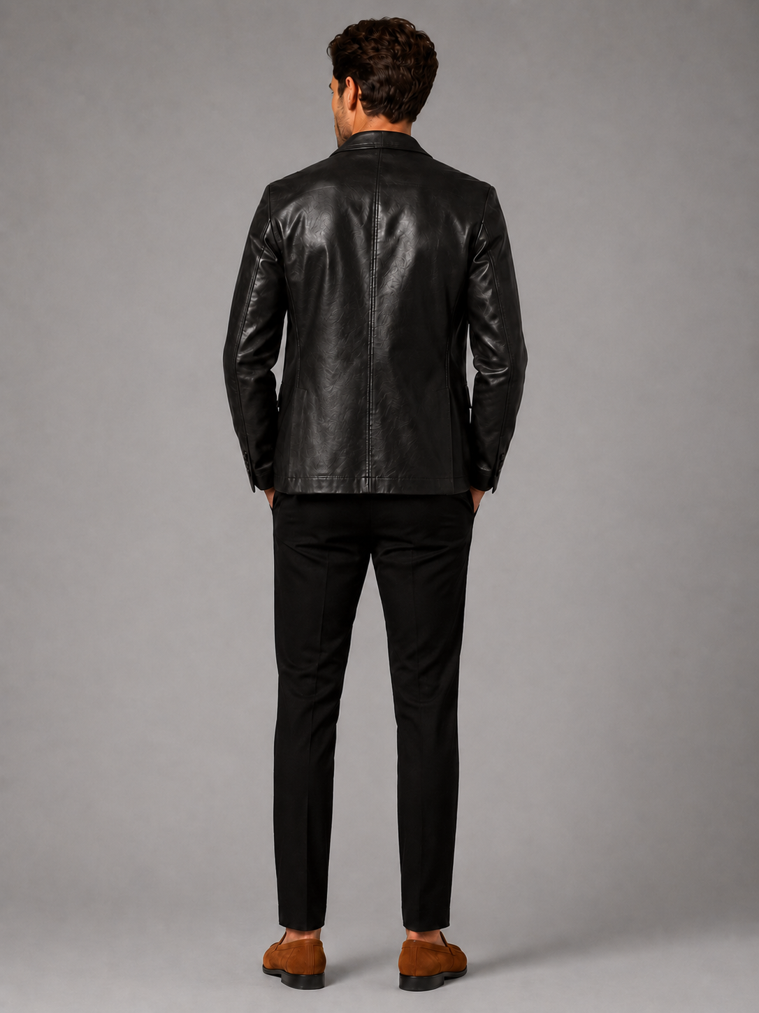 Back view of a man wearing a black leather blazer jacket showing the tailored slim fit, smooth leather finish, and structured silhouette