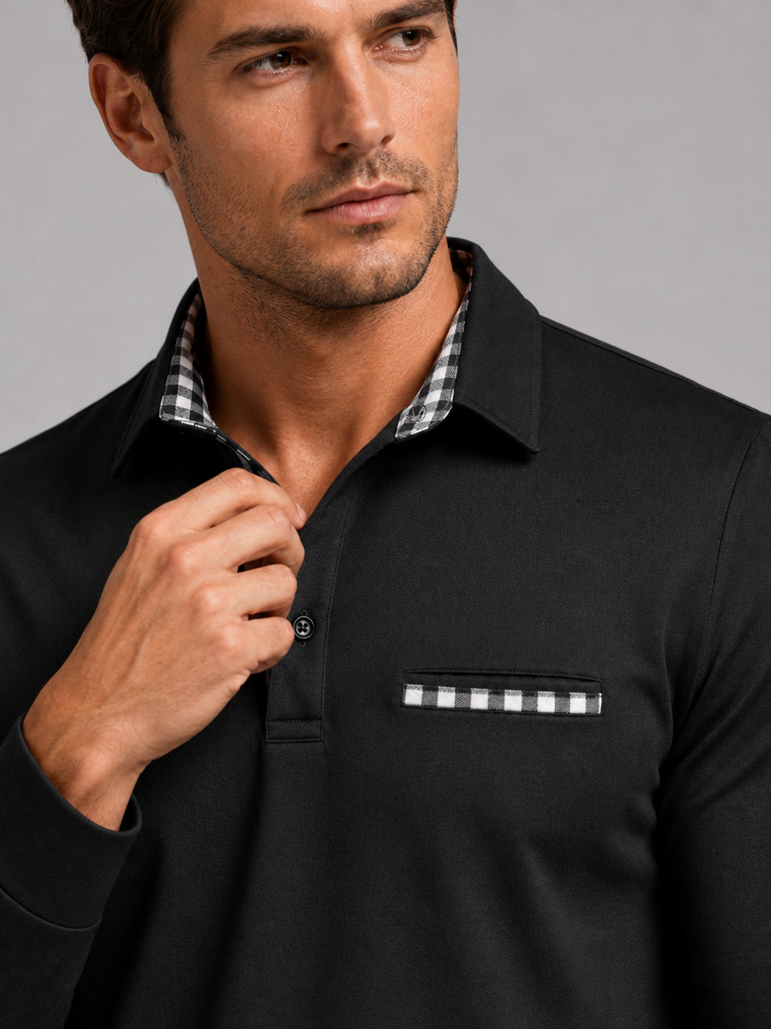 Close up of black polo shirt showing plaid panel detail, soft fabric, and classic collar