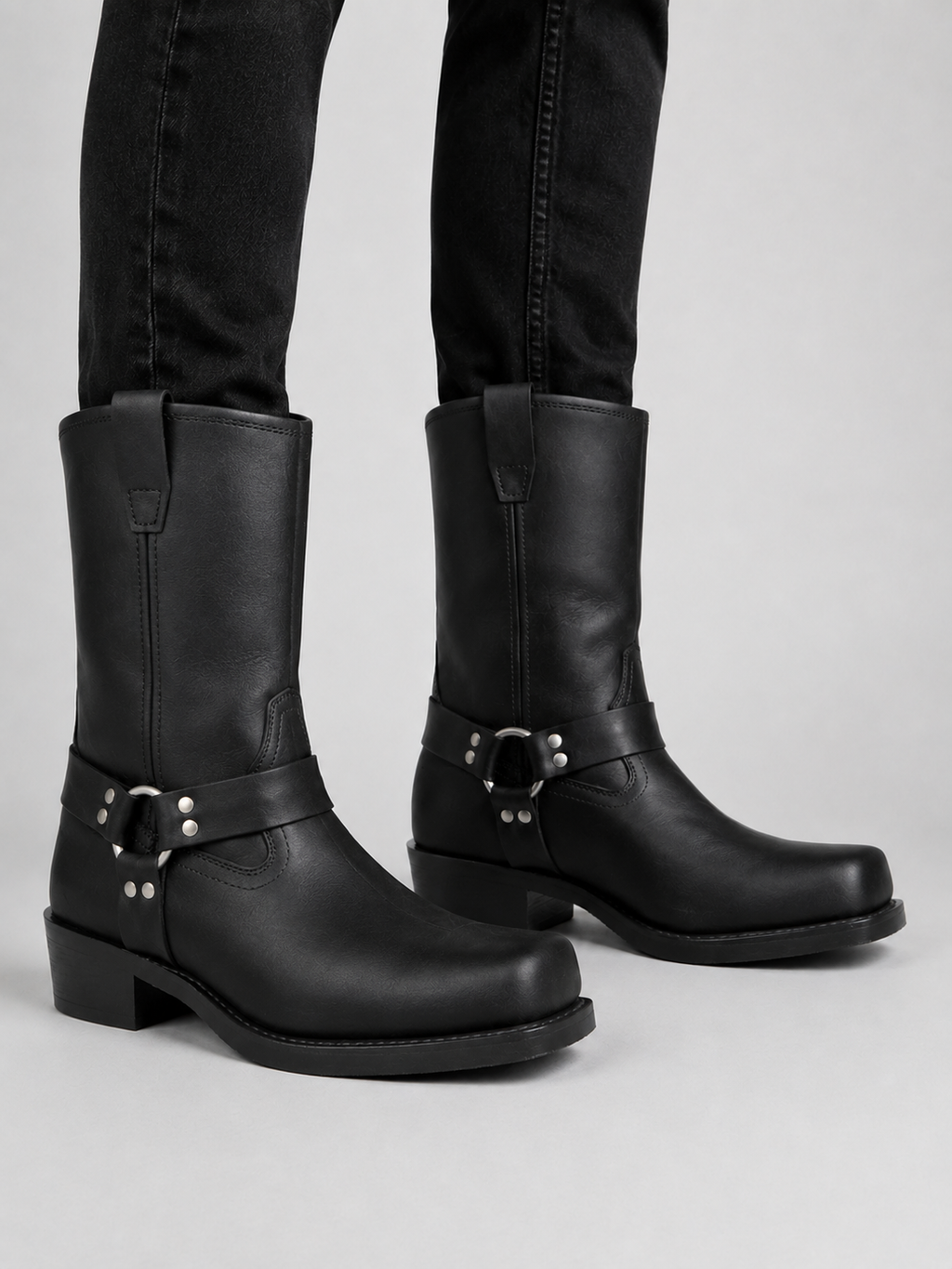 Man wearing black men’s mid calf cowboy boots with a leather upper and slip-on western design in a casual everyday outfit