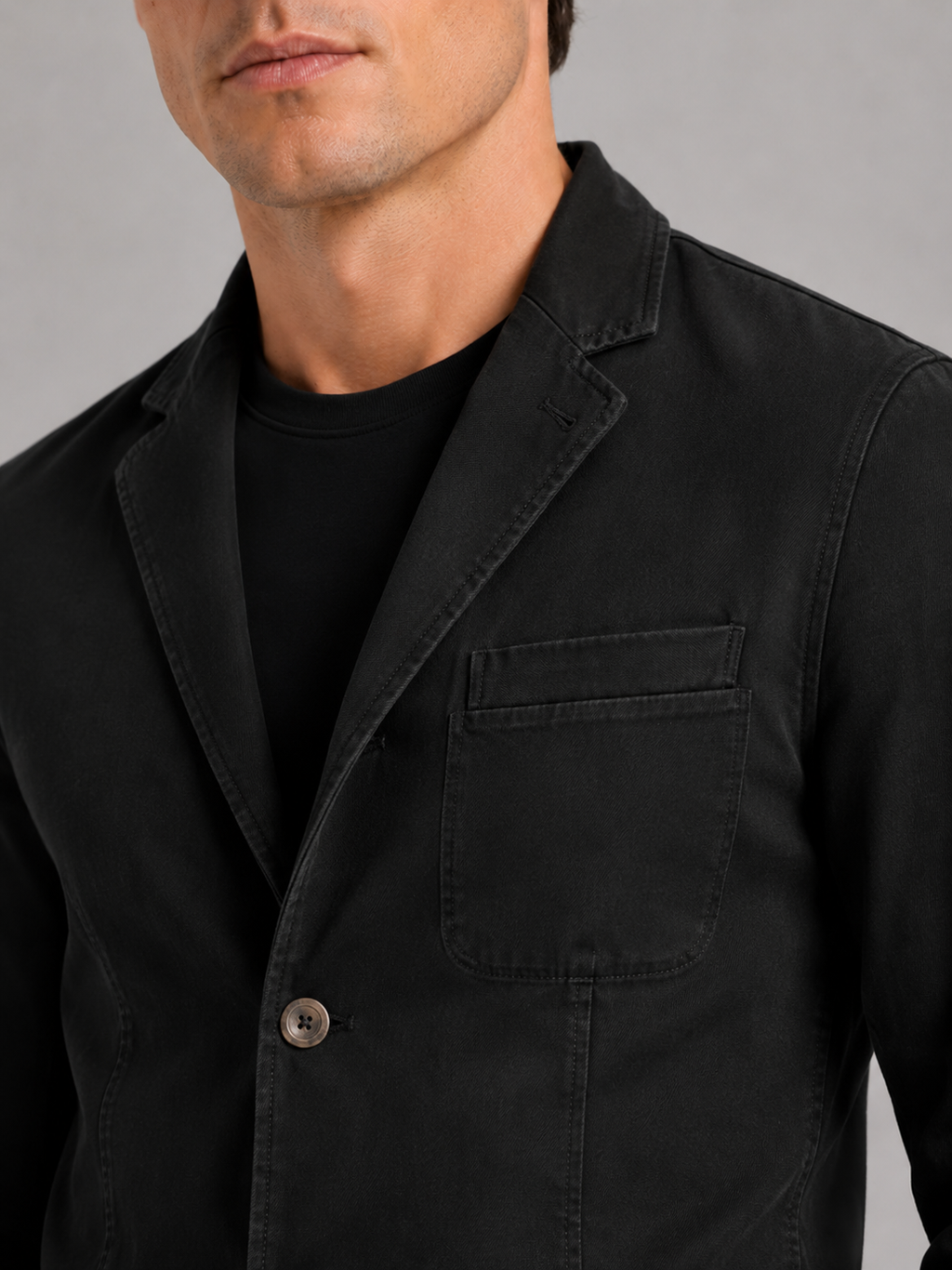 Close up of black washed cotton blazer jacket showing soft texture and tailored lapel detail