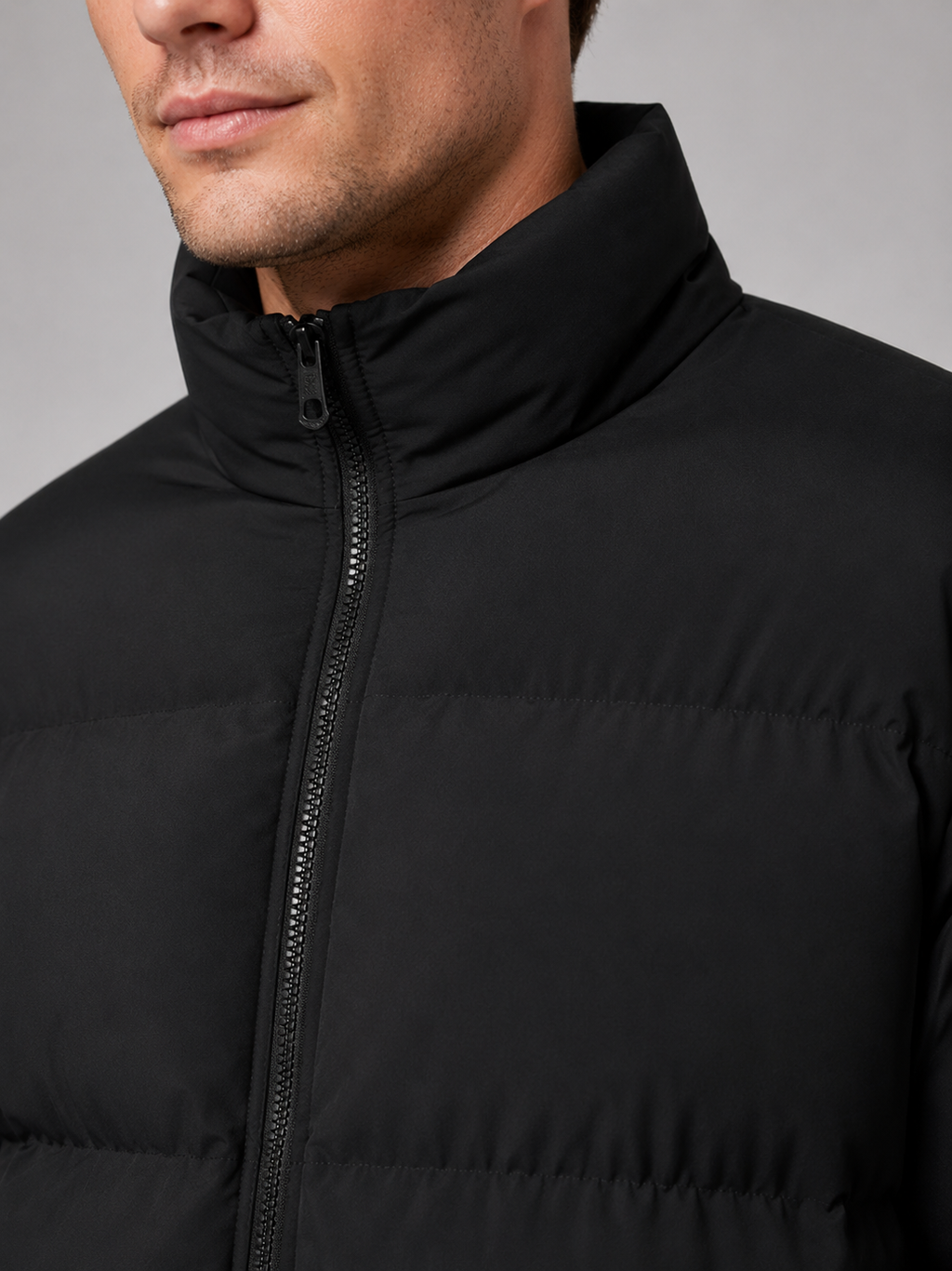 Close up of black puffer jacket showing insulated quilted construction and stand collar detail