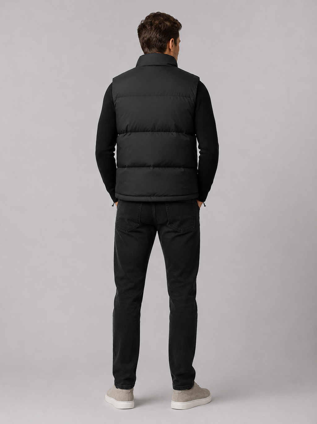 Back view of a man wearing a black puffer vest showing the quilted construction, stand collar, and comfortable fit