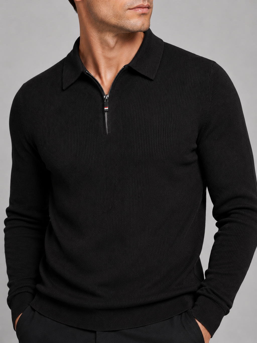 Close-up of a black quarter zip long sleeve polo showing the zipper closure, lapel collar, soft fabric texture, cuffs, hem, and stitching