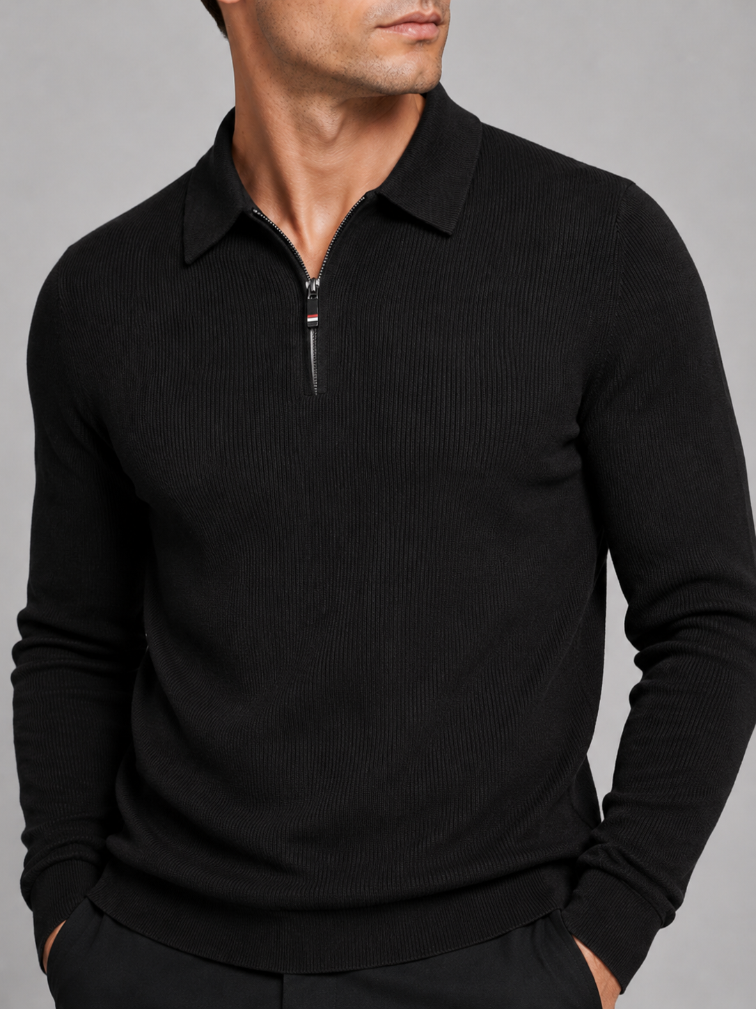 Close-up of a black quarter zip long sleeve polo showing the zipper closure, lapel collar, soft fabric texture, cuffs, hem, and stitching