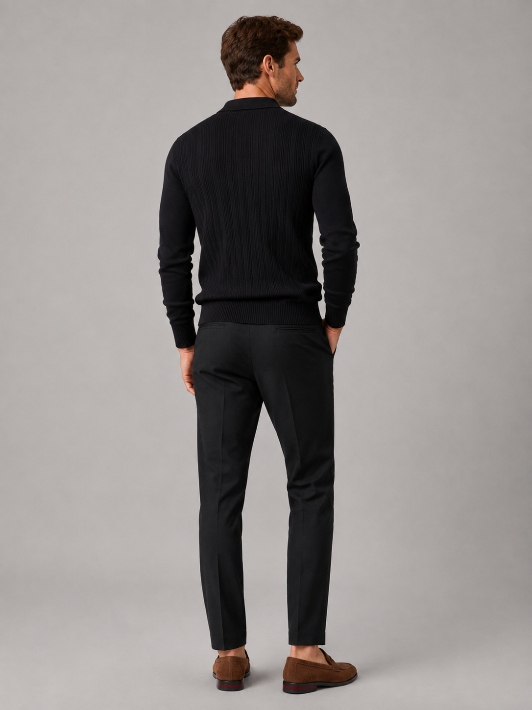 Back view of a man wearing a black quarter zip polo shirt showing the slim fit, long sleeves, and textured fabric construction