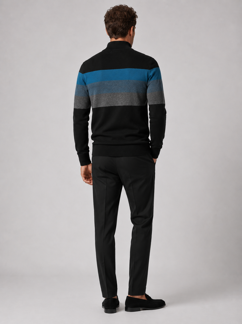 Back view of a man wearing a black cotton quarter zip sweater showing the patchwork design and relaxed fit