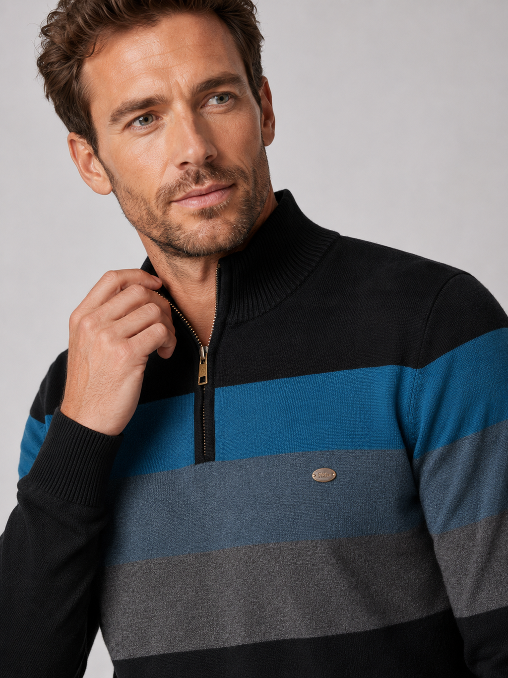 Close-up of a black patchwork quarter zip sweater showing the cotton knit texture, mock neck, zipper, and stitching