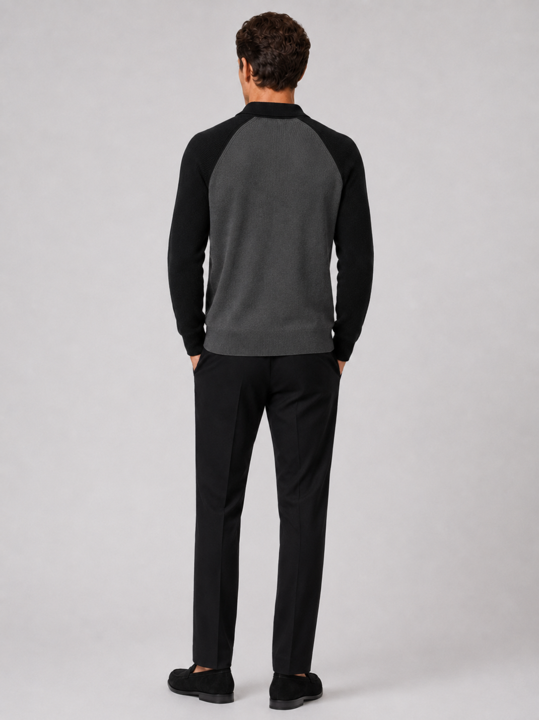 Back view of a man wearing a black quarter zip knit polo sweater showing the slim fit and long sleeves