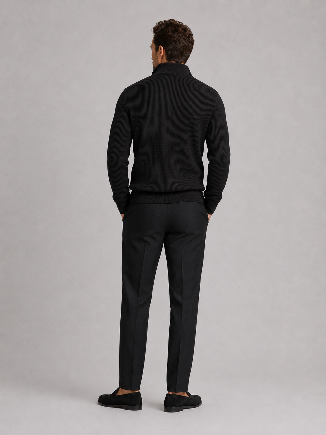 Back view of a man wearing a black quarter zip sweater showing the slim fit, long sleeves, and clean knit finish
