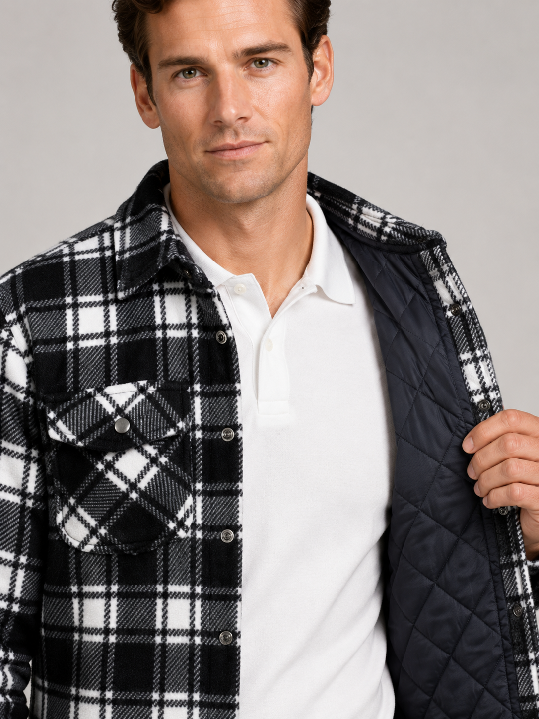 Close up of black quilted jacket showing plaid flannel lining, quilted stitching, and durable fabric detail