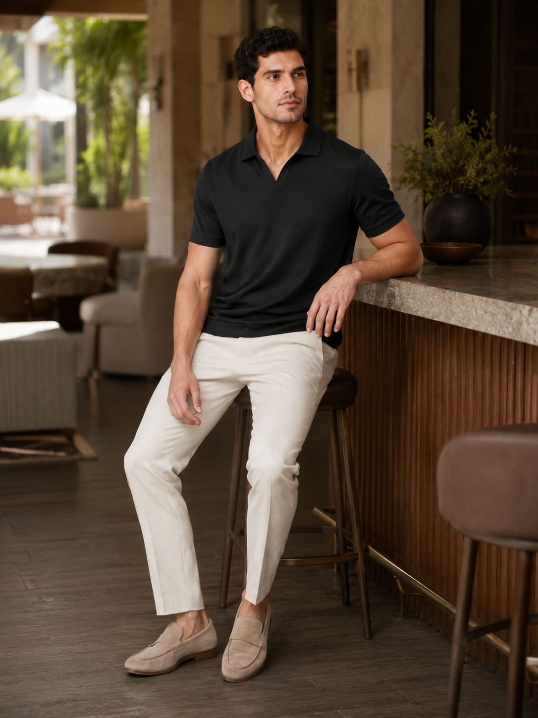 Man styling black silky polo shirt in a refined summer lifestyle outfit for business casual wear