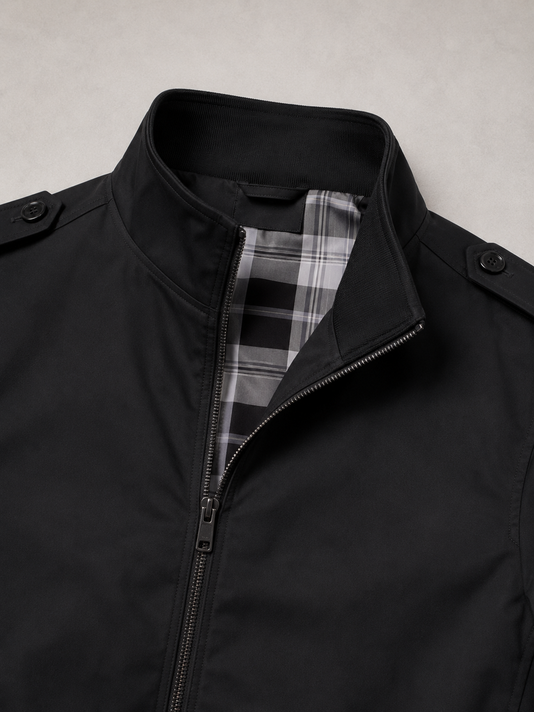 Close up of black trench jacket showing smooth lightweight fabric and stand collar detail