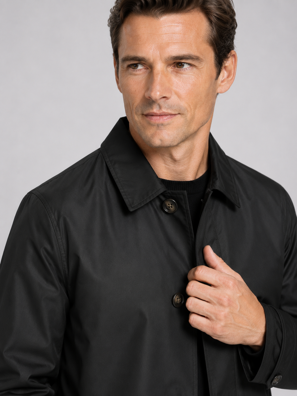 Close up of black trench coat showing structured lapel, button up front, and premium fabric detail