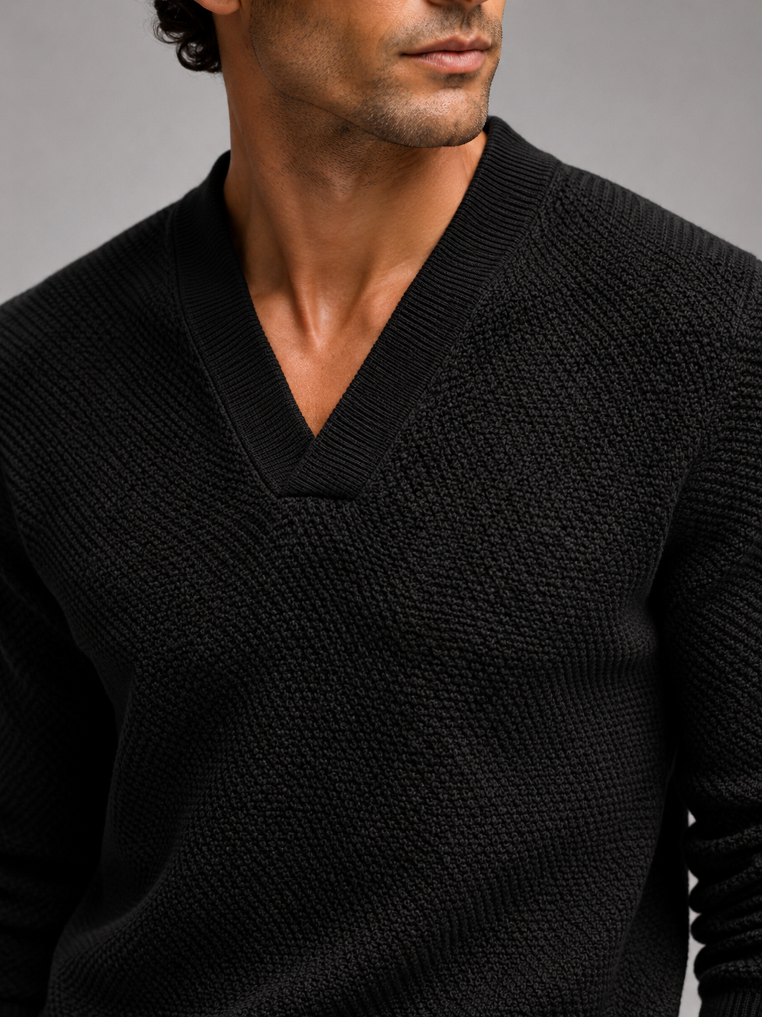 Close up of black knit sweater showing thick warm fabric and refined v neck detail