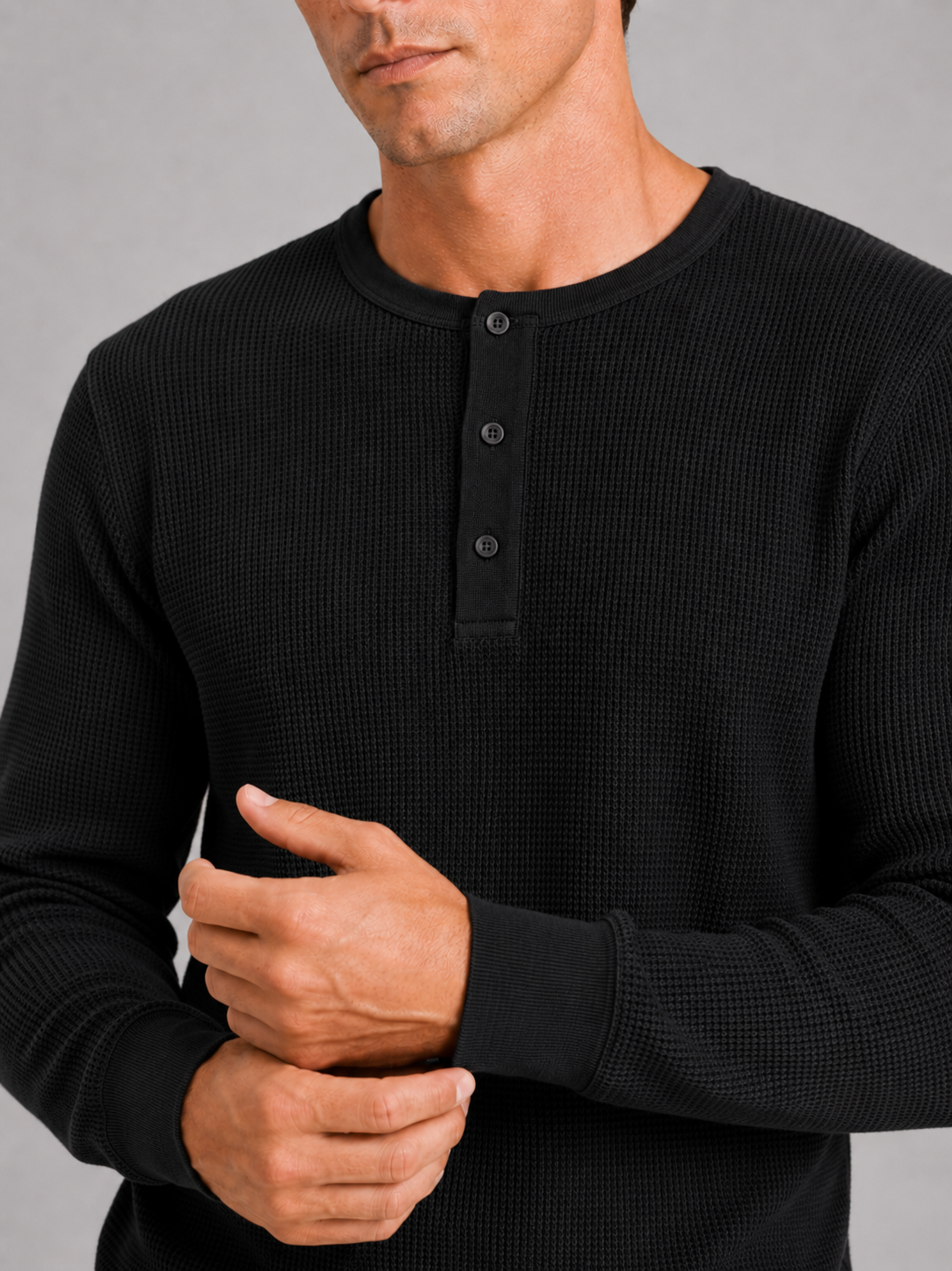Close up of black waffle knit henley showing breathable textured fabric and button detail