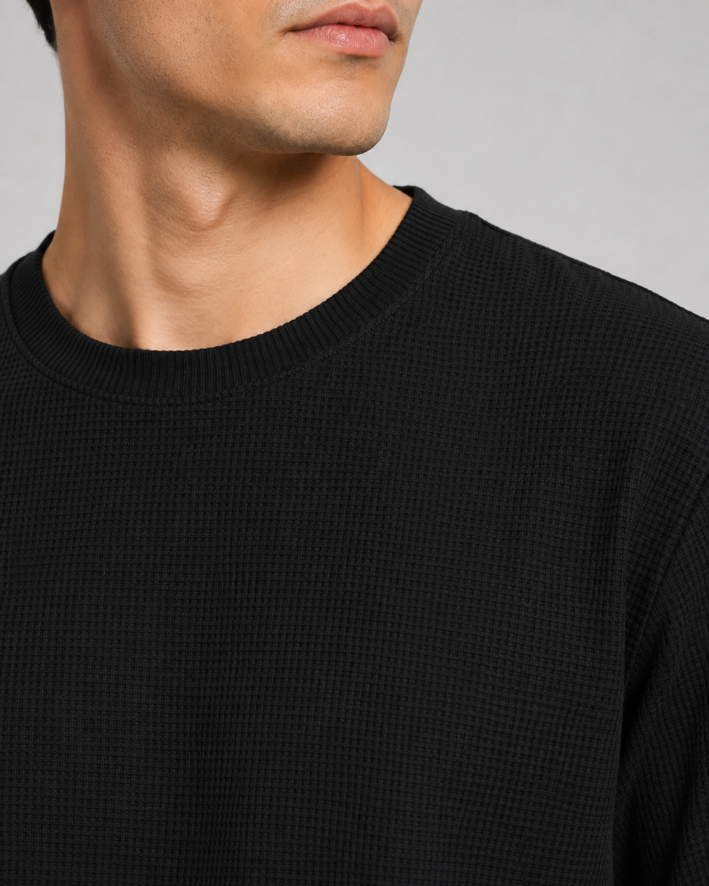 Close up of black waffle knit fabric showing soft breathable textured weave and lightweight finish