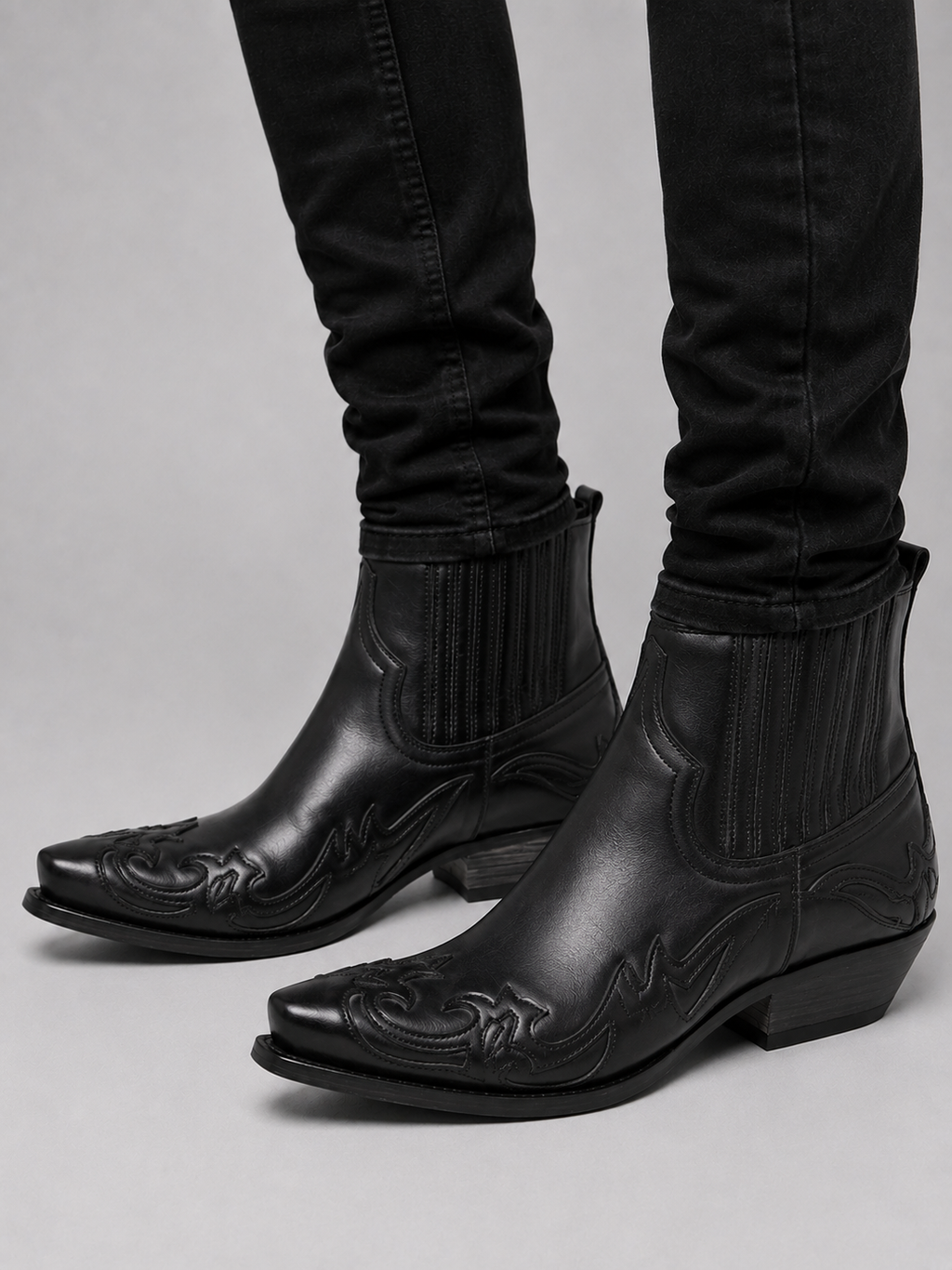 Man wearing black western cowboy boots with embroidered leather and pointed toe in a casual everyday outfit