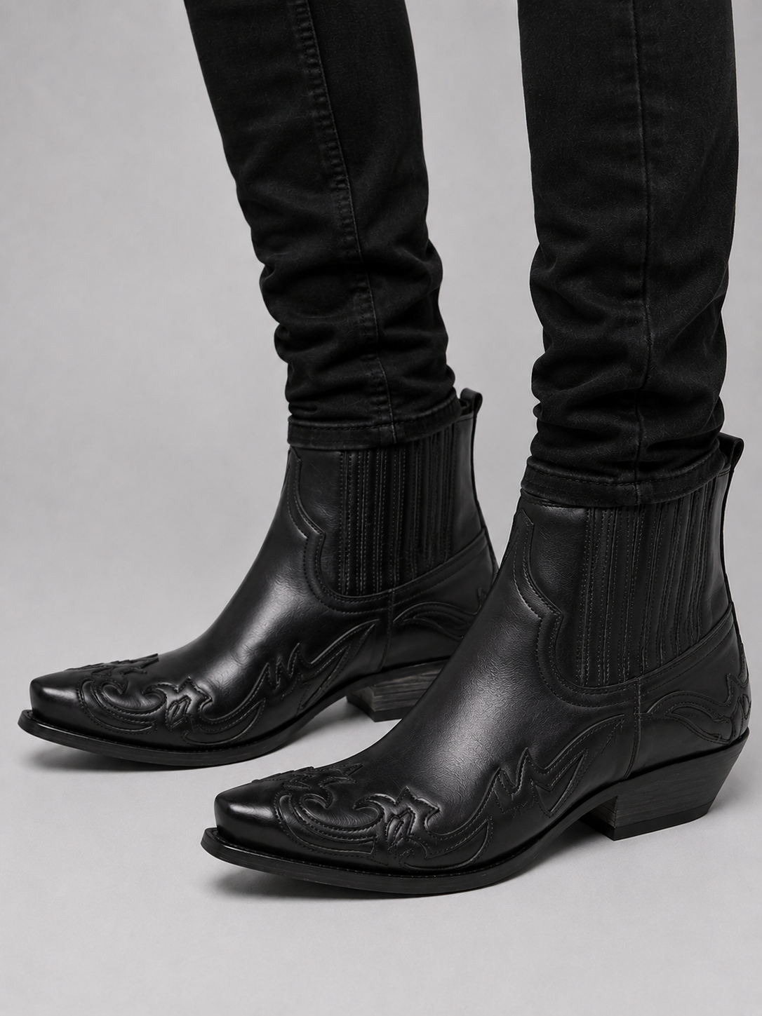 Man wearing black western cowboy boots with embroidered leather and pointed toe in a casual everyday outfit