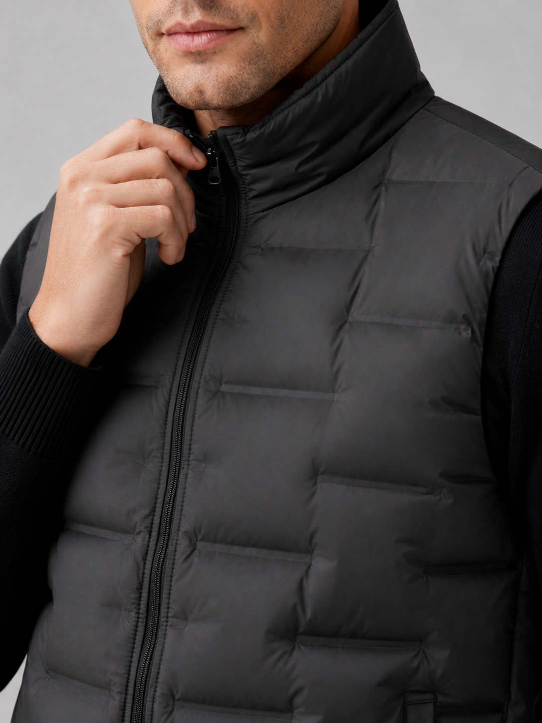 Close up of black white duck down vest showing lightweight quilted insulation, stand collar, and weather resistant fabric detail