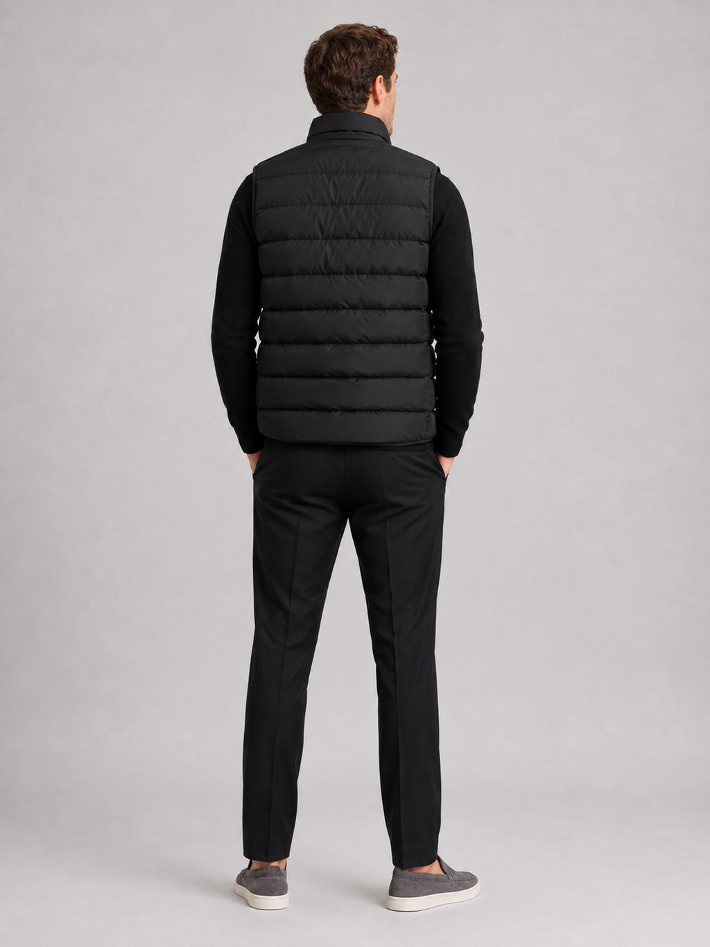 Back view of a man wearing a black puffer vest showing the padded construction, sleeveless cut, and comfortable fit