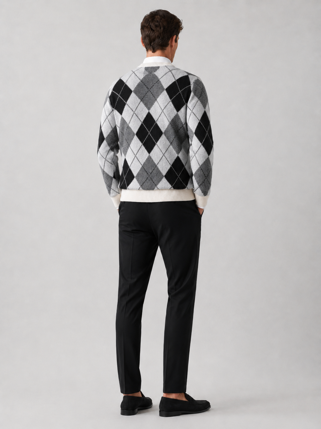 Close-up of a black wool argyle sweater showing the diamond pattern, thick knit texture, crew neckline, ribbed cuffs, and hem