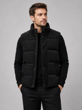 Front view of a man wearing a black corduroy puffer vest with a stand collar, padded construction, and full zip front