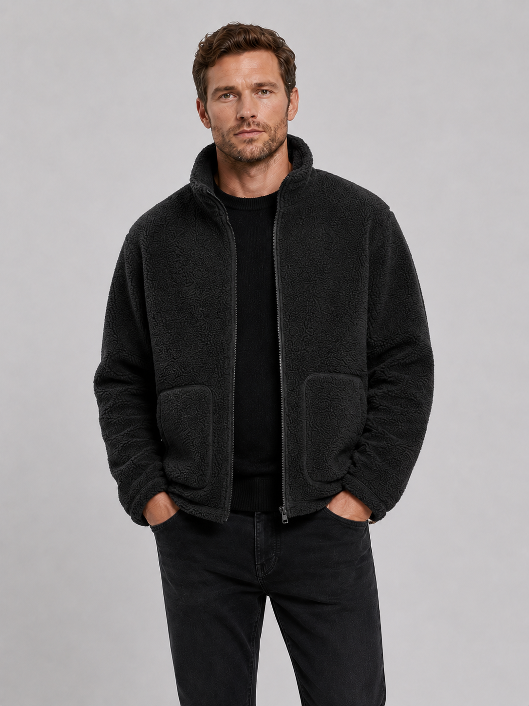 Front view of a man wearing a black full zip fleece jacket with a stand collar, loose fit, long sleeves, and warm fall winter design