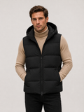 Front view of a man wearing a black hooded puffer vest with thick insulation, a full zip front, and sleeveless winter design