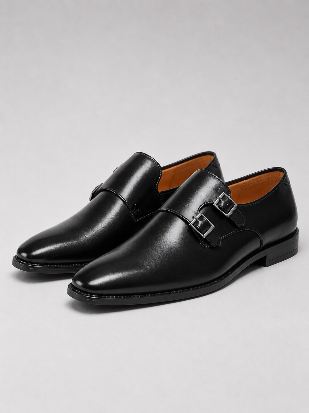 Close up of black leather monk strap shoes showing polished finish and pointed toe detail