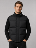 Front view of a man wearing a black puffer vest with a thick insulated design, stand collar, and full zip front