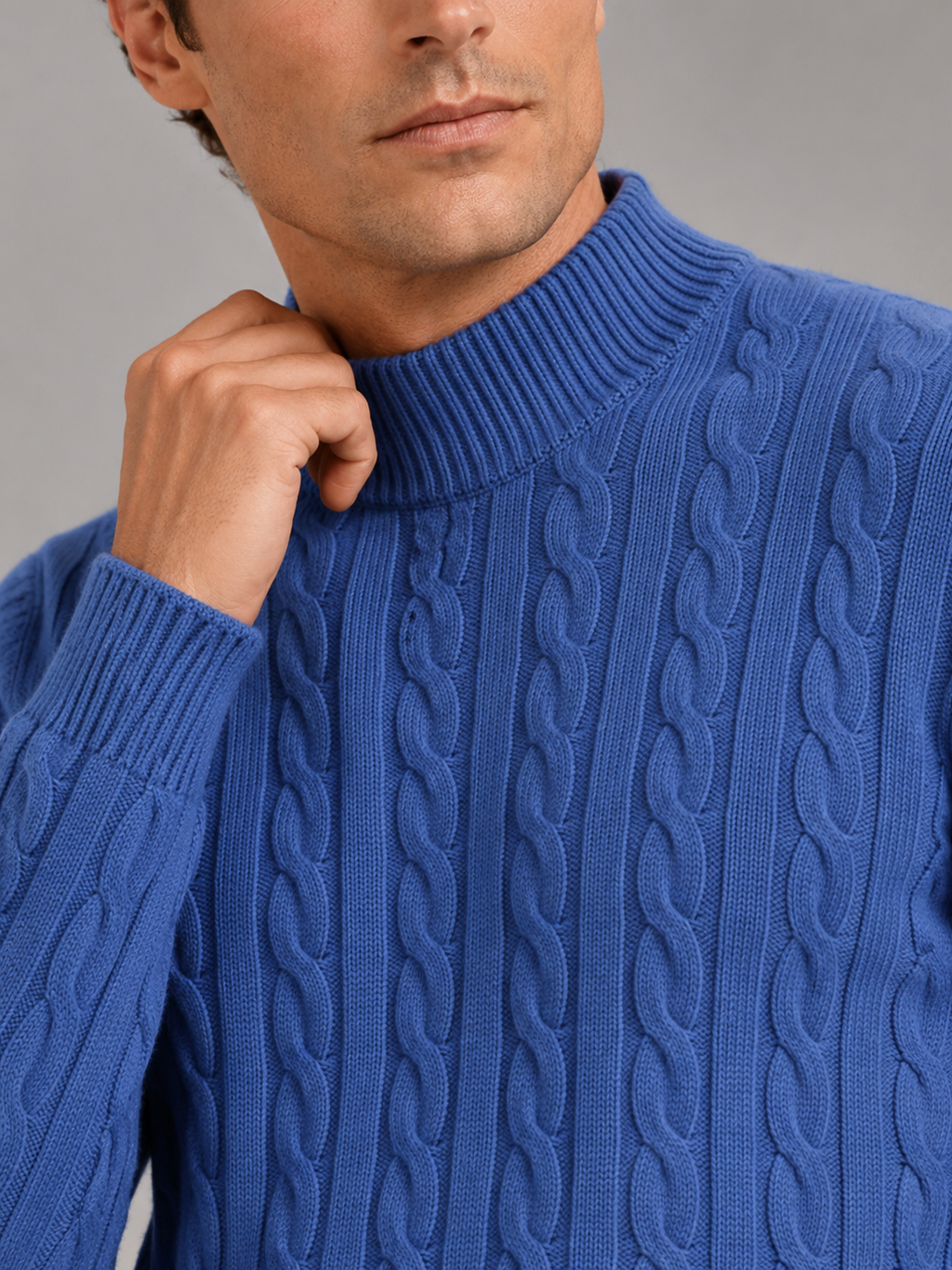 Close up of blue wool cable knit sweater showing soft texture and mock neck detail