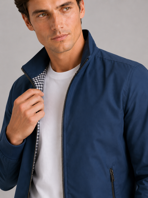 Close up of blue bomber jacket showing smooth fabric and refined zipper collar detail