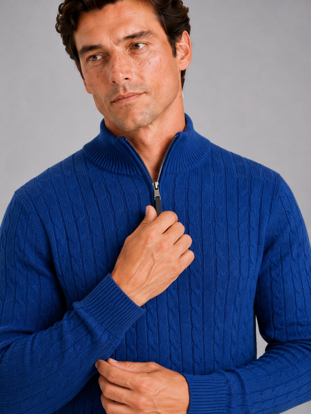 Close up of blue cable knit sweater showing thick textured fabric and quarter zip detail