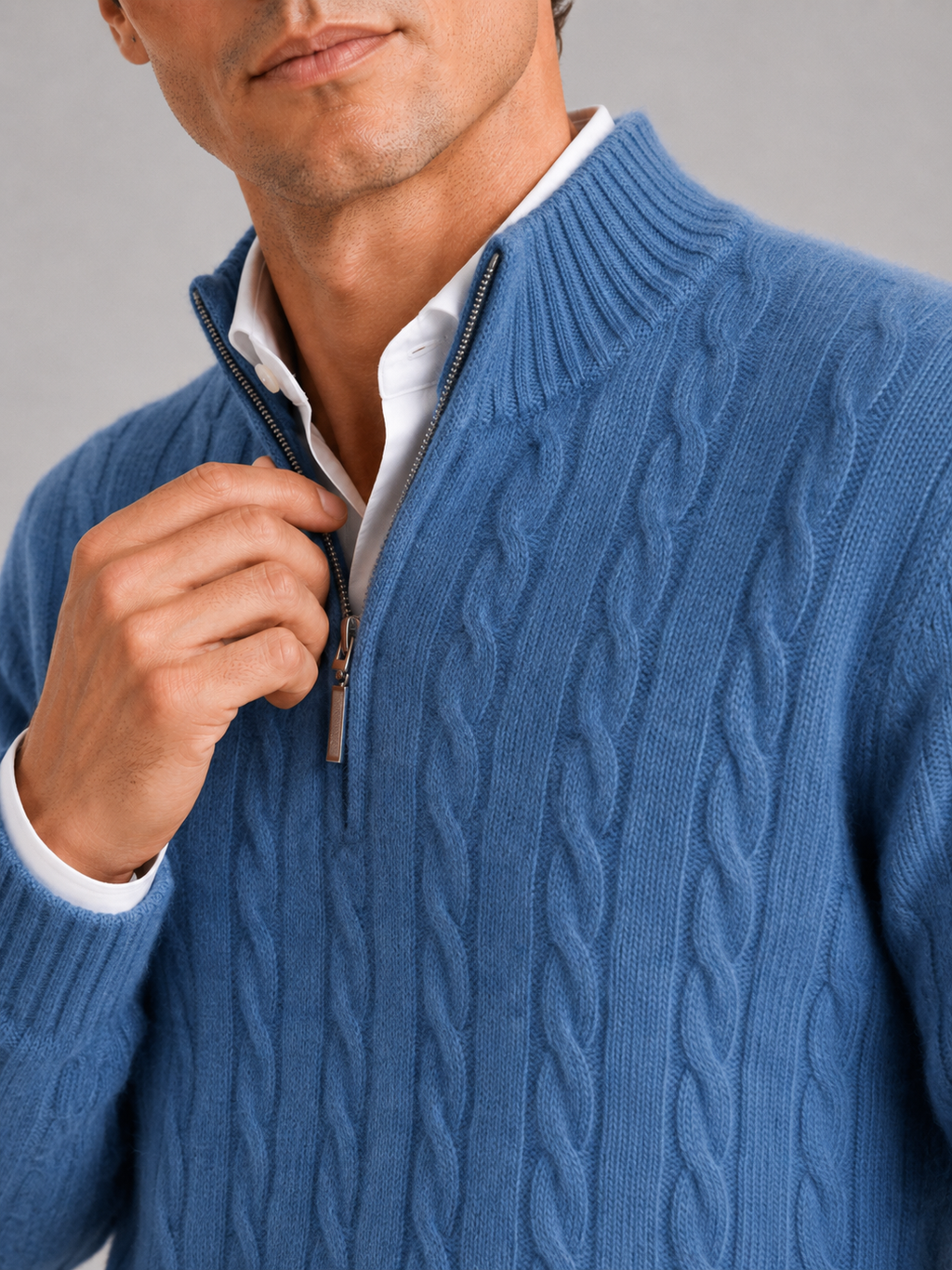 Close up of blue cashmere sweater showing soft cable knit texture and quarter zip detail
