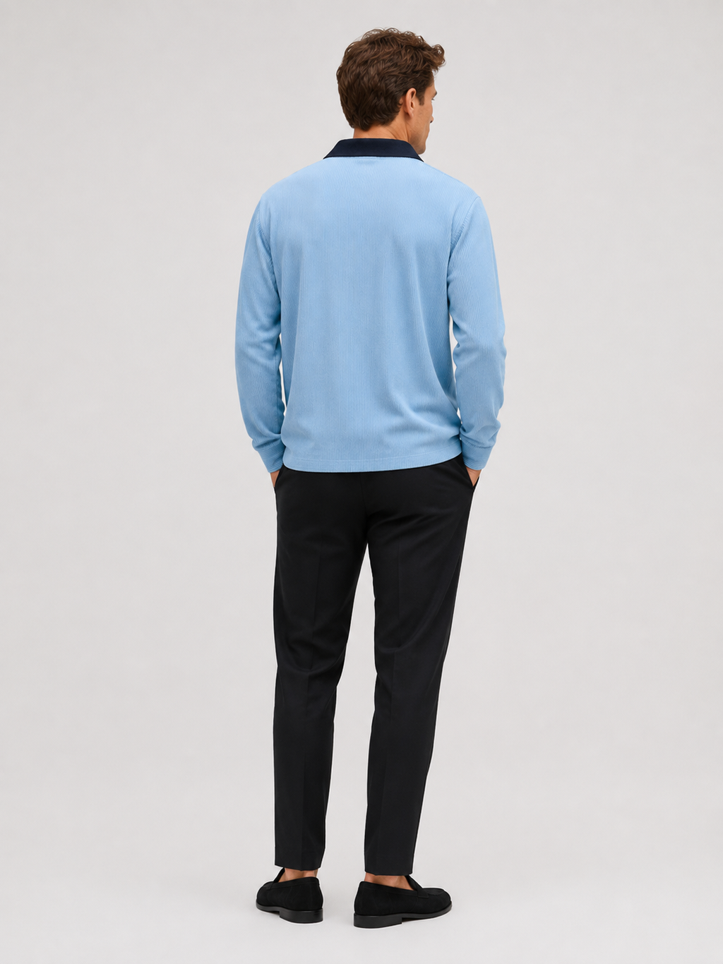 Back view of a man wearing a blue corduroy polo shirt showing the long sleeves, relaxed fit, and soft textured fabric