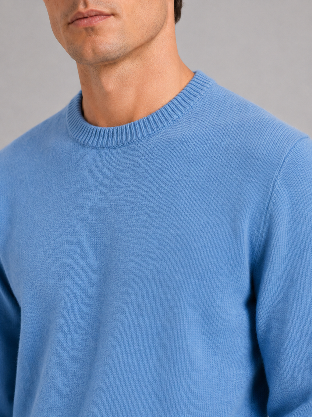 Close up of blue knit sweater showing soft textured fabric and classic crew neck detail