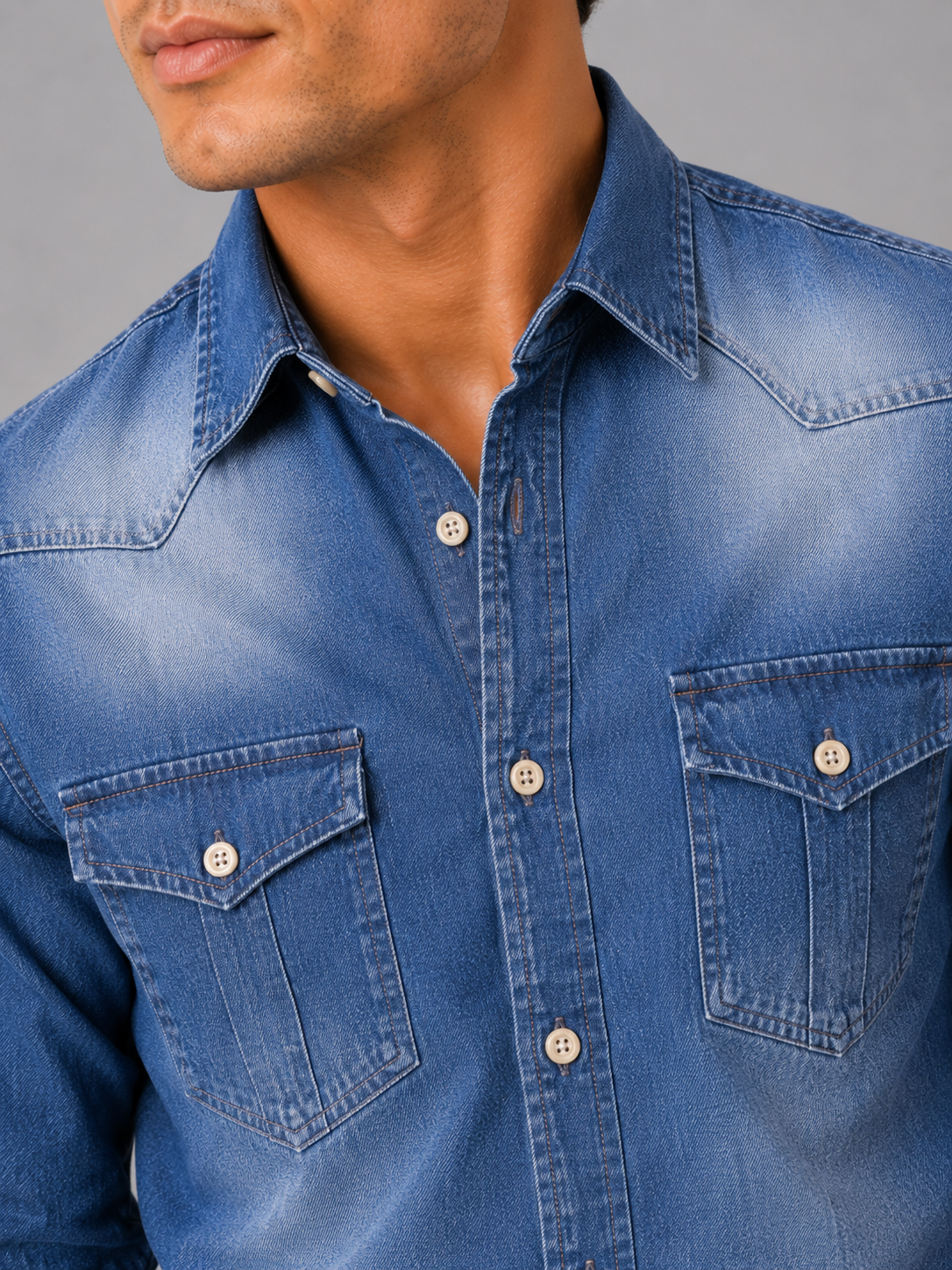 Close up of blue denim shirt showing washed cotton texture and button up detail