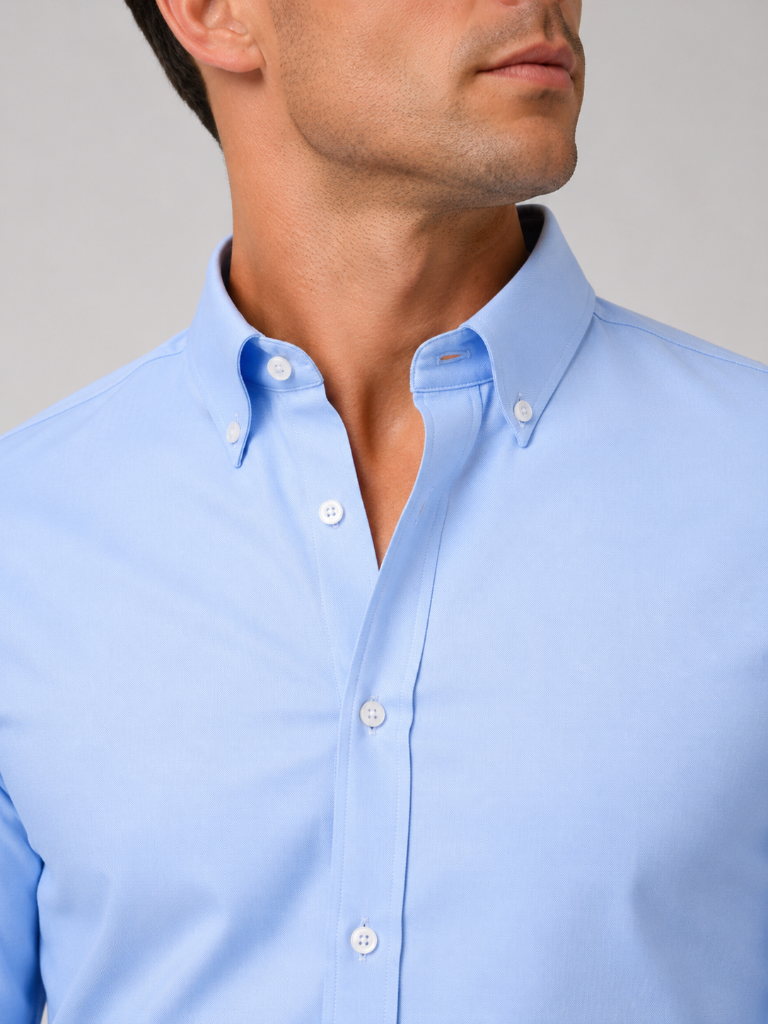 Close up of blue oxford shirt showing soft cotton fabric and refined button up detail