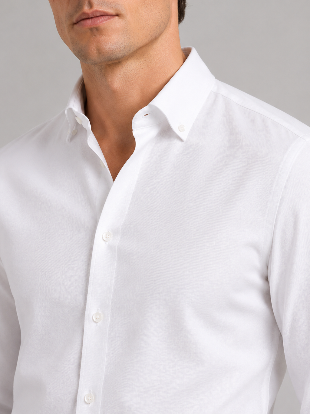Close up of white oxford shirt showing soft cotton fabric and refined button up detail