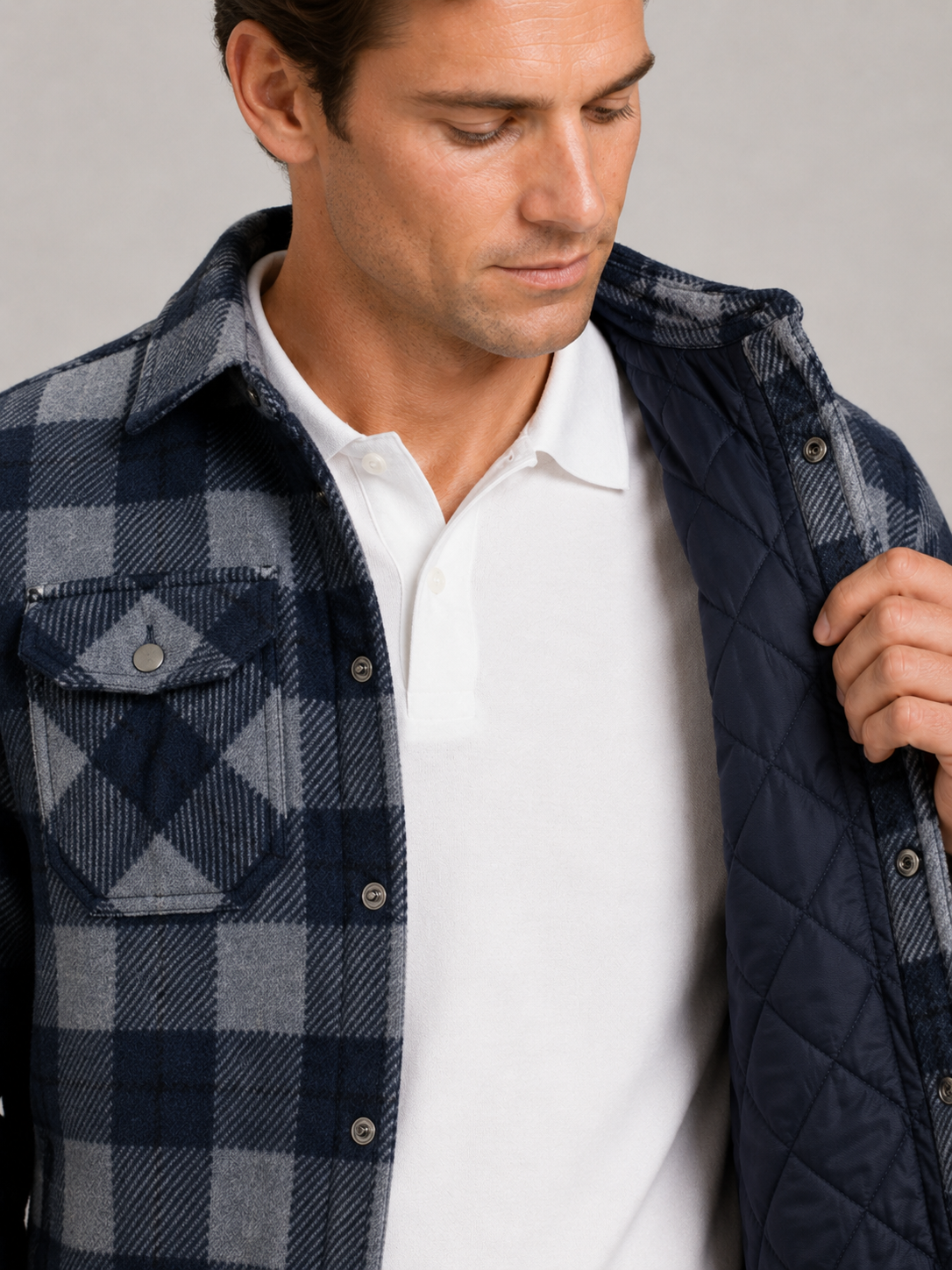 Close up of blue quilted jacket showing plaid flannel lining, quilted stitching, and durable fabric detail