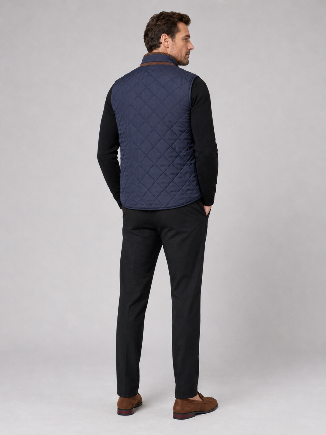 Back view of a man wearing a blue quilted vest showing the padded construction, sleeveless cut, and comfortable fit