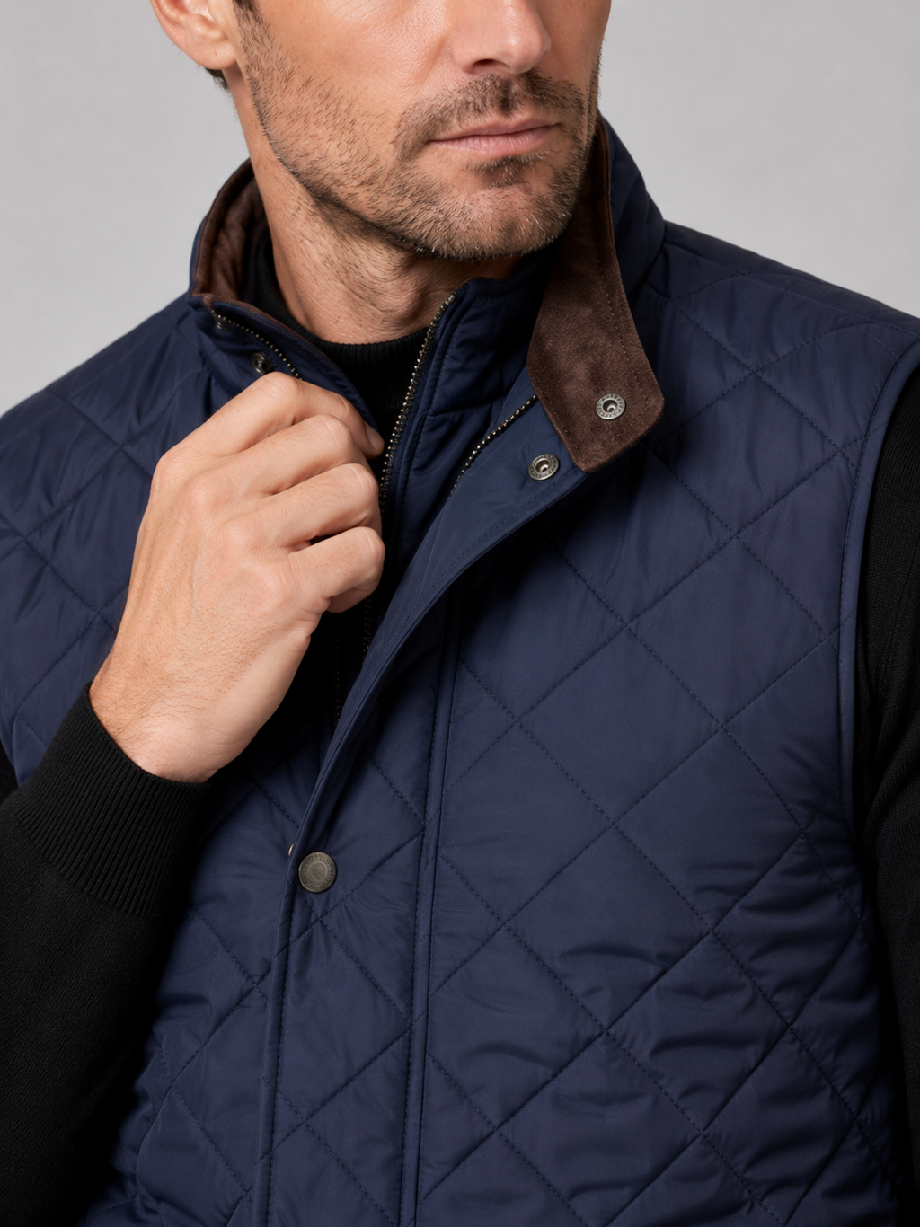 Close-up of a blue quilted vest showing the stitched pattern, polo collar, thick padding, front closure, utility pockets, armholes, and reinforced seams