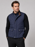 Front view of a man wearing a blue quilted vest with a polo collar, padded construction, and multiple utility pockets