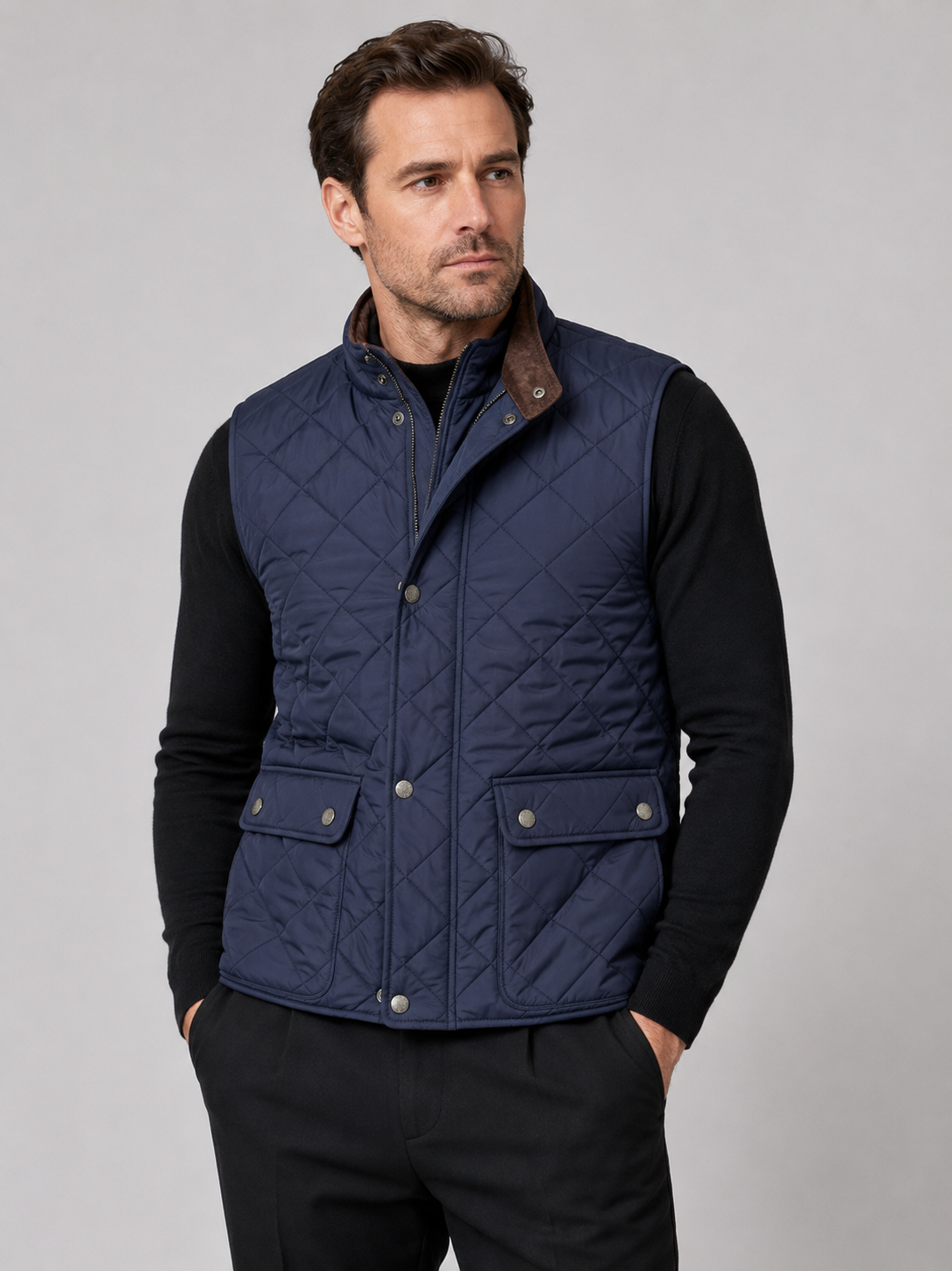 Front view of a man wearing a blue quilted vest with a polo collar, padded construction, and multiple utility pockets