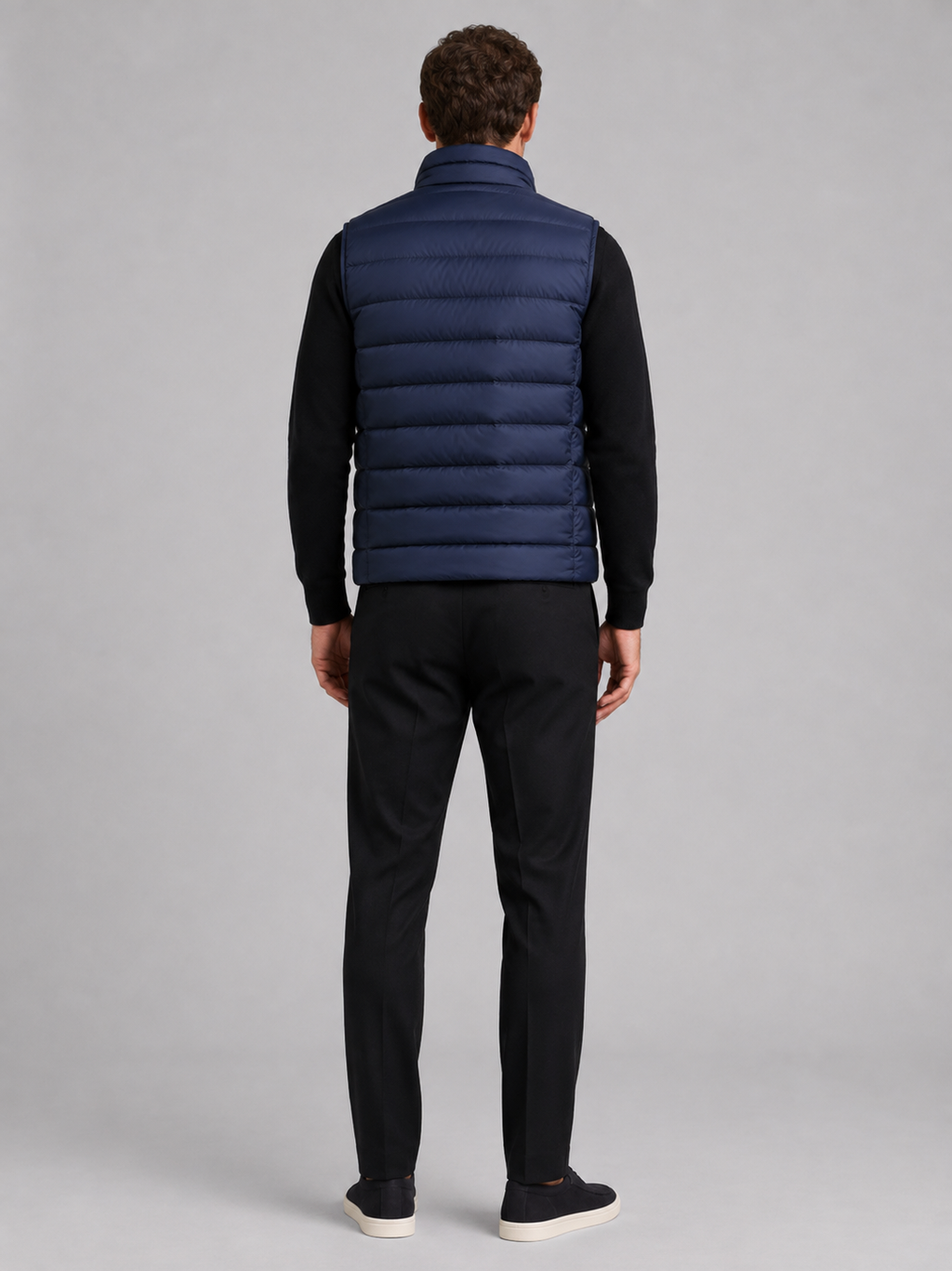 Back view of a man wearing a blue puffer vest showing the padded construction, sleeveless cut, and comfortable fit