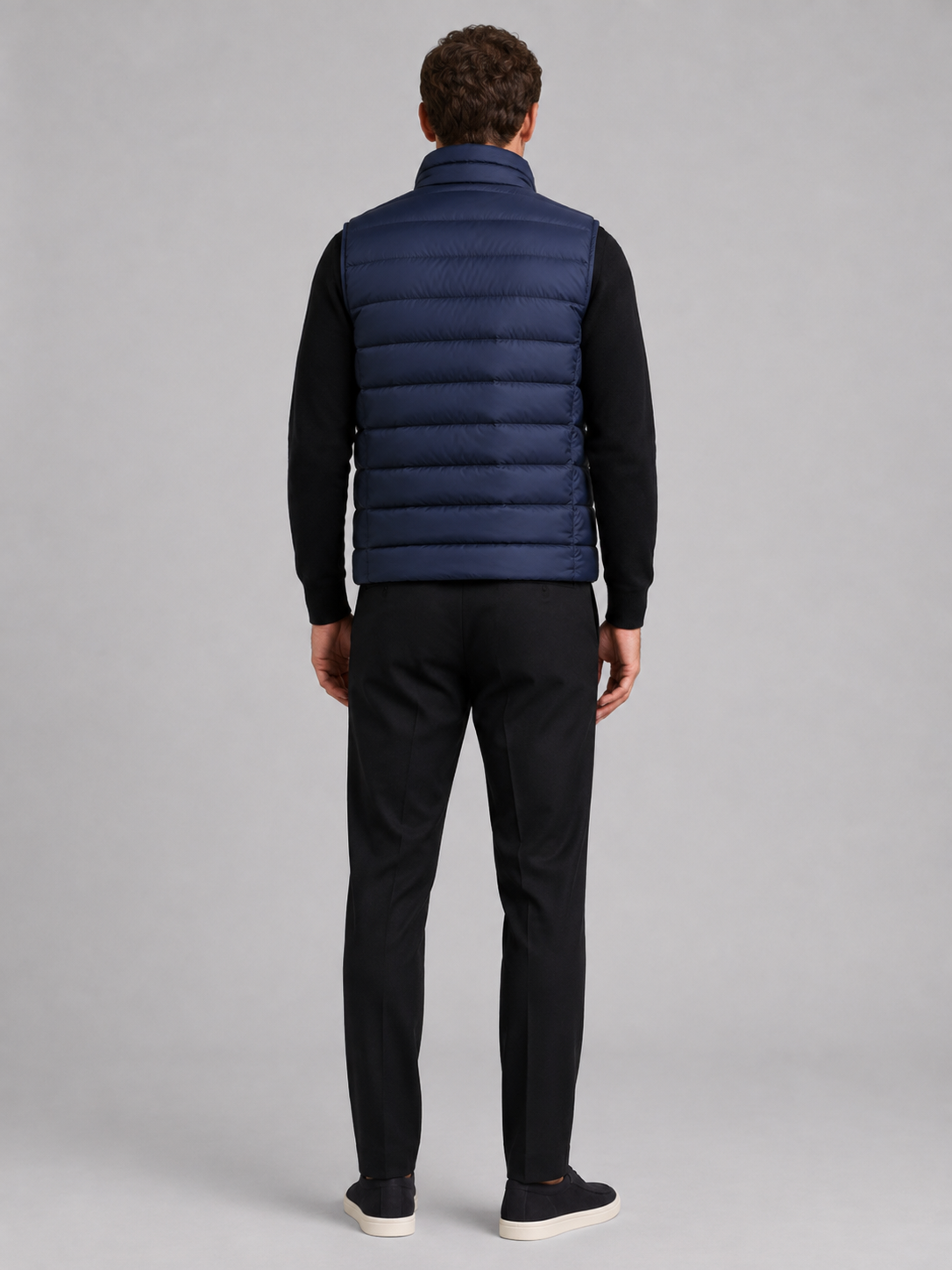 Back view of a man wearing a blue puffer vest showing the padded construction, sleeveless cut, and comfortable fit