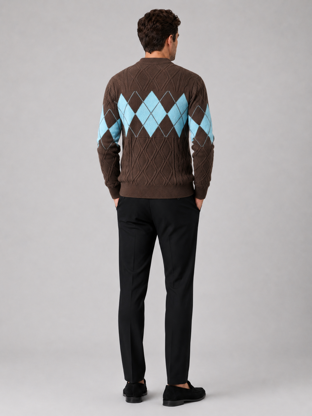 Back view of a man wearing a brown argyle cable knit sweater showing the mock neck, long sleeves, thick knit fabric, and comfortable fit